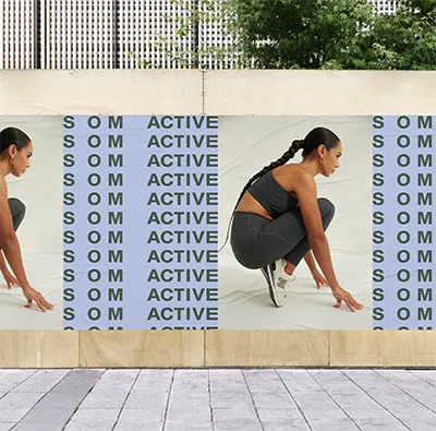 Street poster mockup of a model crouching in SOM Active, framed by the brand name repeated on a lilac background
