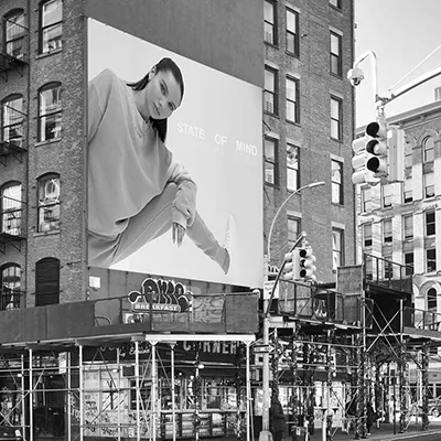 Black and white billboard mockup on a city building, showing a model in a SOM Active set with the words 'State of Mind
